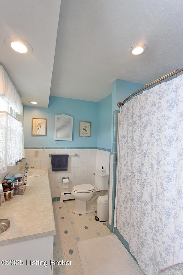 930 Castlewood Dr, New Albany, IN 47150 - bathroom with a baseboard radiator, tile walls, toilet, vanity, and a wainscoted wall