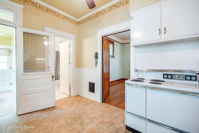 4714 Burkley Ave, Louisville, KY 40214 - kitchen featuring white range with electric stovetop, wallpapered walls, a wainscoted wall, white cabinetry, and light floors