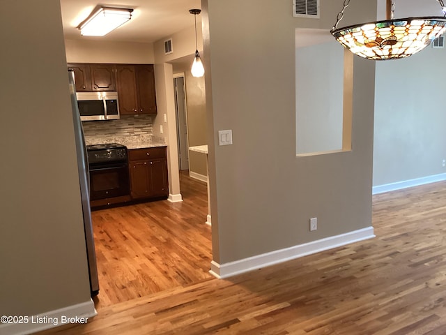 1815 Gardiner Ln Unit A9, Louisville, KY 40205 - kitchen featuring stainless steel microwave, black range, light wood-type flooring, backsplash, and dark brown cabinets