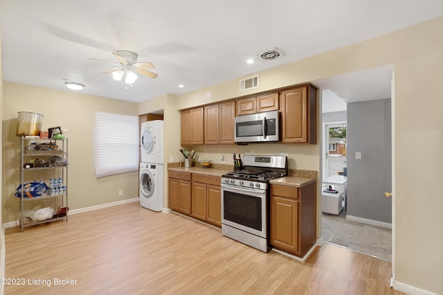 7917 Edsel Ln, Louisville, KY 40291 - kitchen with stainless steel appliances, stacked washing machine and dryer, ceiling fan, light wood finished floors, and baseboards