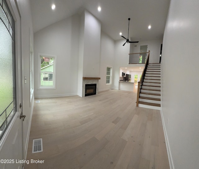 6702 Shirley Ave, Prospect, KY 40059 - unfurnished living room with light wood-type flooring, high vaulted ceiling, a high end fireplace, baseboards, and stairway