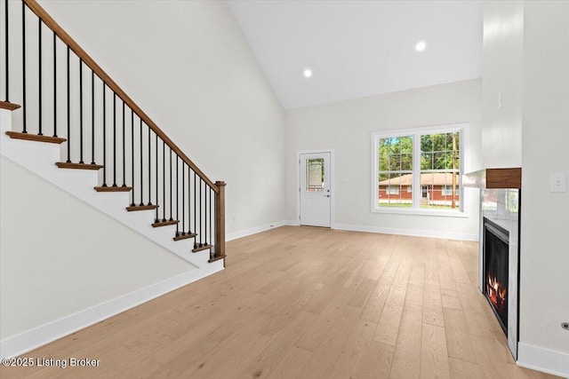 6702 Shirley Ave, Louisville, KY 40059 - foyer with high vaulted ceiling, light wood finished floors, a warm lit fireplace, stairway, and recessed lighting