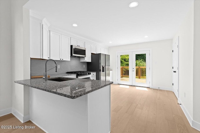 6702 Shirley Ave, Louisville, KY 40059 - kitchen featuring appliances with stainless steel finishes, a sink, light wood-type flooring, dark stone countertops, and backsplash