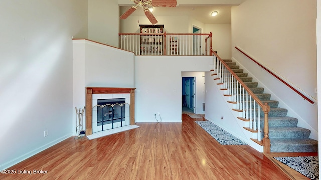 512 Valley College Dr, Louisville, KY 40272 - unfurnished living room with ceiling fan, a towering ceiling, wood finished floors, stairs, and baseboards