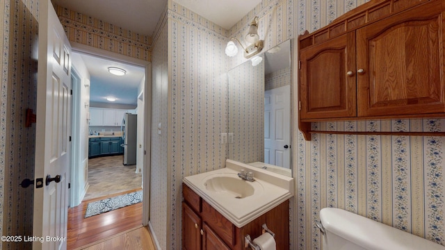 512 Valley College Dr, Louisville, KY 40272 - bathroom with wallpapered walls, toilet, vanity, and wood finished floors
