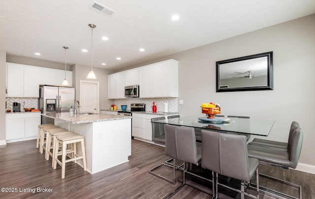 17121 Piton Way, Louisville, KY 40245 - kitchen featuring appliances with stainless steel finishes, tasteful backsplash, a sink, a breakfast bar, and dark wood-style flooring