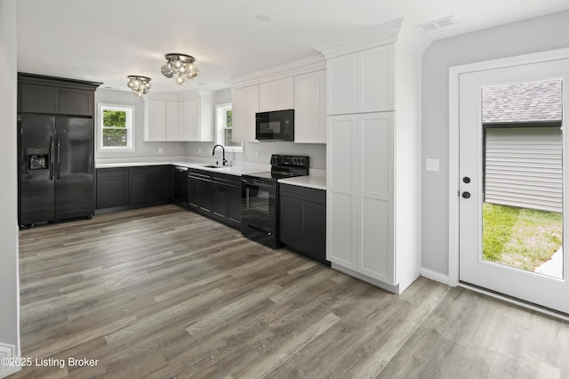 802 Kentucky Ave, Frankfort, KY 40601 - kitchen featuring black appliances, a sink, light countertops, light wood-style floors, and white cabinets