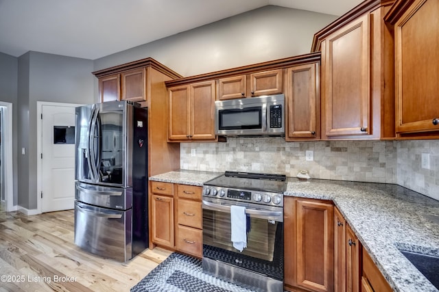 4605 Clarkhurst Cir, Smithfield, KY 40068 - kitchen featuring appliances with stainless steel finishes, light wood-style flooring, brown cabinets, light stone countertops, and vaulted ceiling
