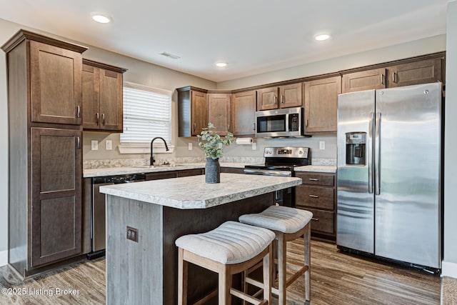 10938 Pheasant Hill Cir, Louisville, KY 40229 - kitchen featuring stainless steel appliances, a sink, wood finished floors, light countertops, and a kitchen bar