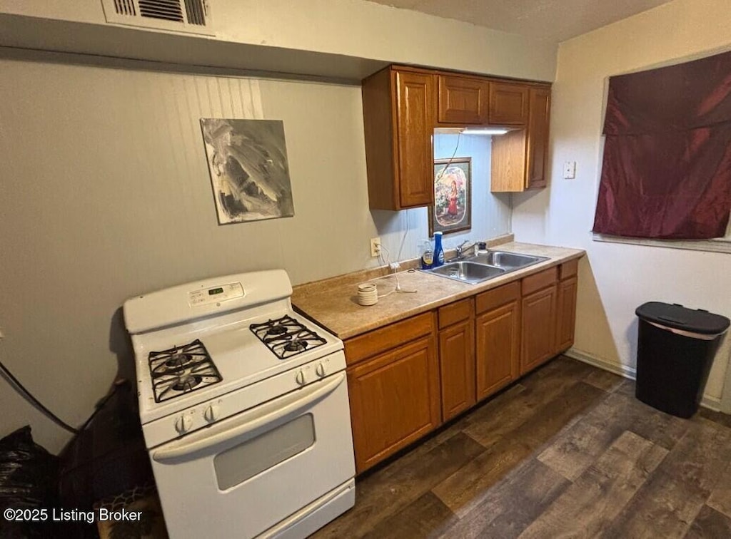 1625 Clara Ave, Louisville, KY 40215 - kitchen featuring white gas stove, a sink, dark wood-style floors, and brown cabinets