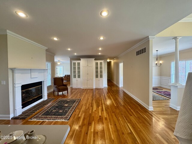144 Woodhill Rd, Bardstown, KY 40004 - unfurnished living room with ornamental molding, wood finished floors, a glass covered fireplace, decorative columns, and plenty of natural light