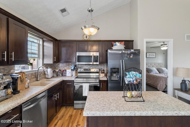 238 Crossfield Dr, Mt Washington, KY 40047 - kitchen with stainless steel appliances, a sink, vaulted ceiling, dark brown cabinets, and a center island