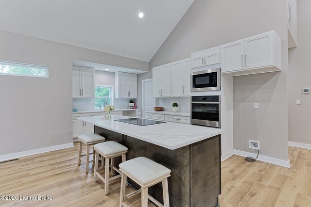 2519 Belknap Beach Rd, Prospect, KY 40059 - kitchen with stainless steel appliances, white cabinets, light wood-style floors, tasteful backsplash, and a breakfast bar