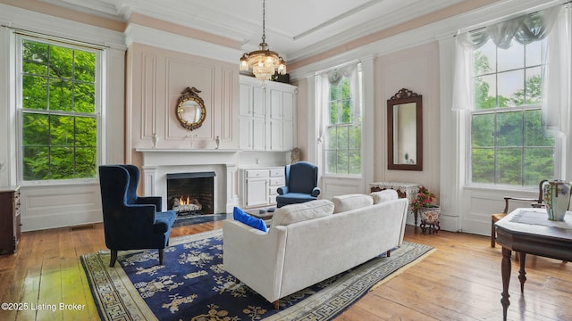 316 E Cross Main St, New Castle, KY 40050 - living room featuring light wood-type flooring, plenty of natural light, a fireplace with flush hearth, ornamental molding, and a chandelier