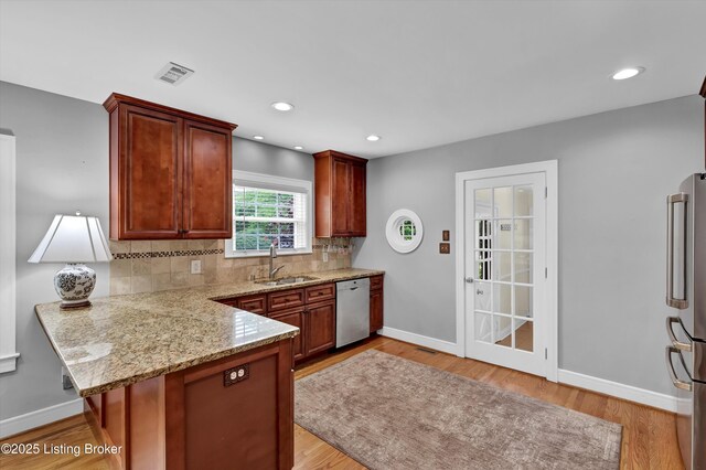 2501 Newburg Rd, Louisville, KY 40205 - kitchen featuring a sink, appliances with stainless steel finishes, a peninsula, decorative backsplash, and light wood finished floors