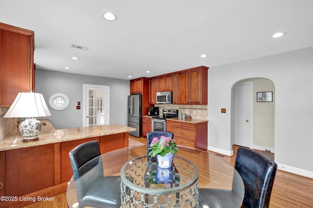 2501 Newburg Rd, Louisville, KY 40205 - kitchen featuring appliances with stainless steel finishes, arched walkways, light wood-style floors, backsplash, and a peninsula