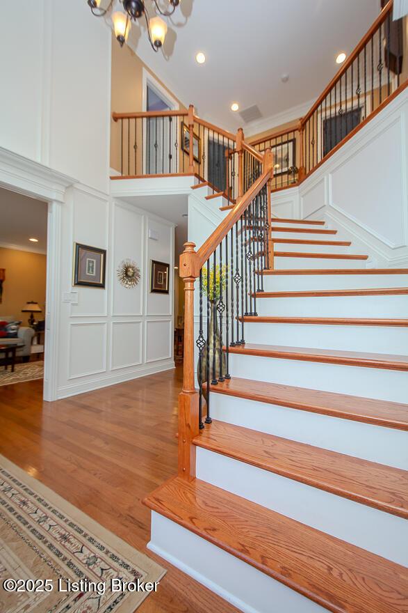 9200 Axminster Dr, Louisville, KY 40299 - stairs with a decorative wall, a high ceiling, a chandelier, wood finished floors, and recessed lighting