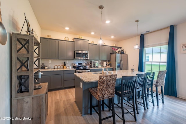 11905 Cascade Falls Trl, Louisville, KY 40229 - kitchen with stainless steel appliances, a center island with sink, light wood-type flooring, tasteful backsplash, and recessed lighting
