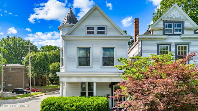 victorian home featuring covered porch and a chimney