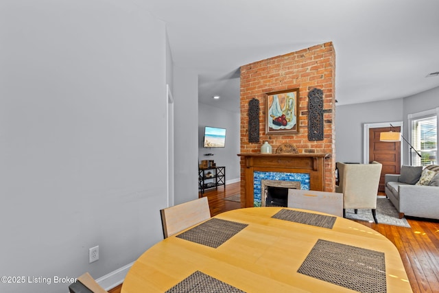 dining space with wood-type flooring, a fireplace, baseboards, and recessed lighting