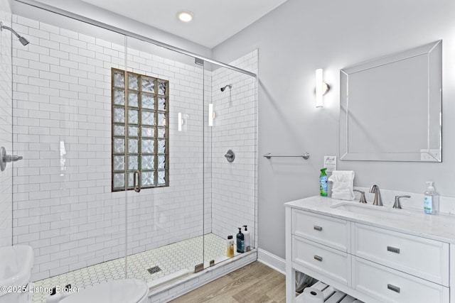 bathroom with toilet, a stall shower, vanity, wood finished floors, and recessed lighting