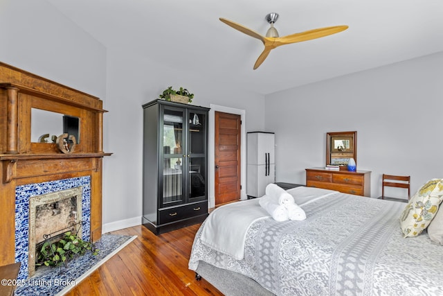 bedroom featuring wood finished floors, a tile fireplace, a ceiling fan, access to exterior, and baseboards