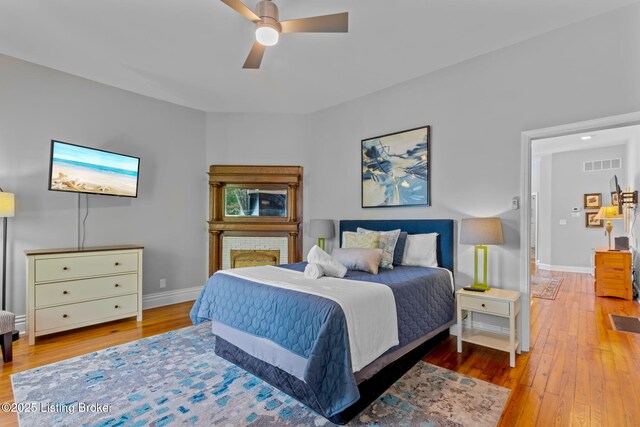 bedroom with light wood finished floors, baseboards, and ceiling fan