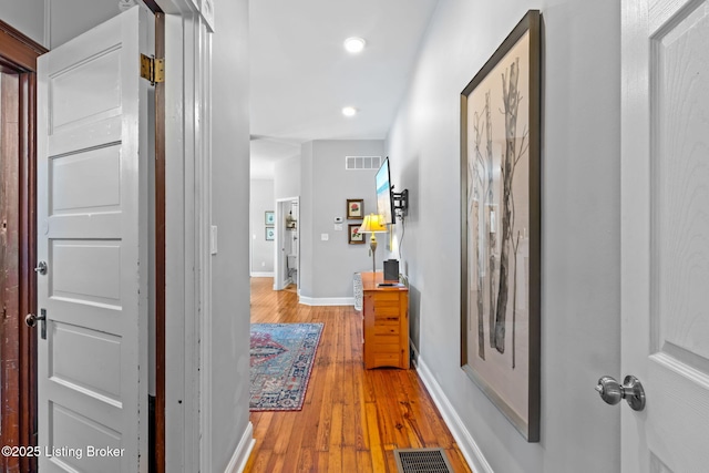 hall featuring light wood-style floors, recessed lighting, and baseboards