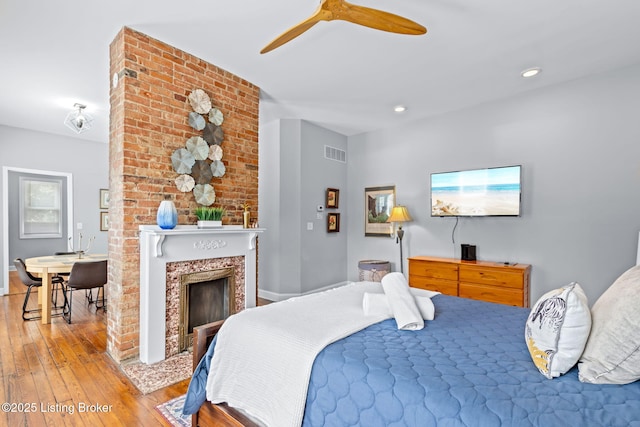 bedroom featuring hardwood / wood-style flooring, a brick fireplace, ceiling fan, and recessed lighting