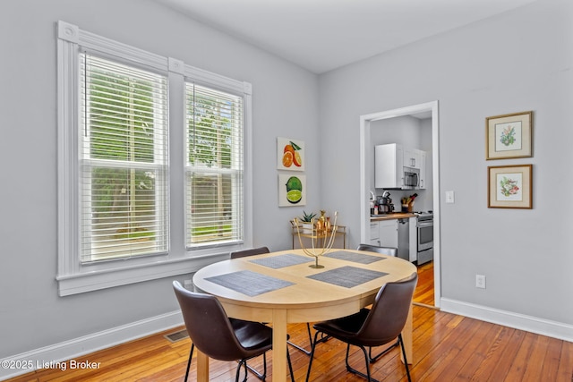 dining area with light wood finished floors and baseboards
