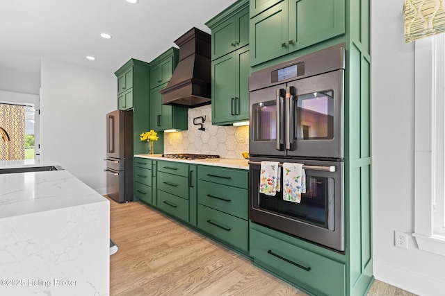 118 Stable Way, Jeffersonville, IN 47130 - kitchen featuring stainless steel appliances, custom range hood, green cabinets, light wood-style floors, and backsplash
