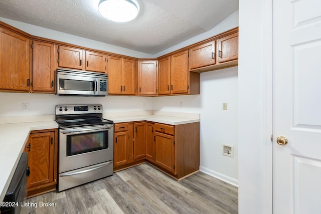 4225 Treesdale Dr, Sellersburg, IN 47172 - kitchen with appliances with stainless steel finishes, brown cabinetry, light wood-style floors, a textured ceiling, and light countertops