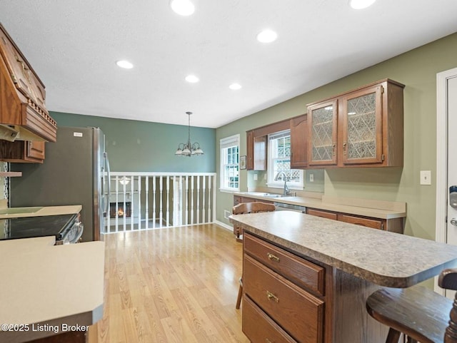 8703 Bards Ct, Louisville, KY 40299 - kitchen with light wood-type flooring, recessed lighting, glass insert cabinets, a chandelier, and brown cabinetry