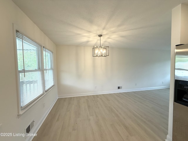 11302 Deering Rd, Louisville, KY 40272 - unfurnished dining area with a chandelier, light wood-type flooring, and a textured ceiling