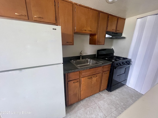 4143 Hillview Ave, Louisville, KY 40216 - kitchen featuring black range with gas stovetop, freestanding refrigerator, a sink, under cabinet range hood, and dark countertops