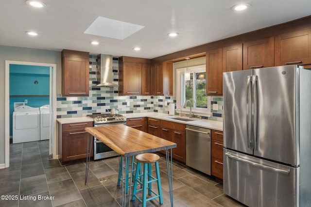 1140 Rostrevor Cir, Louisville, KY 40205 - kitchen with stainless steel appliances, wall chimney range hood, washing machine and dryer, a sink, and a skylight