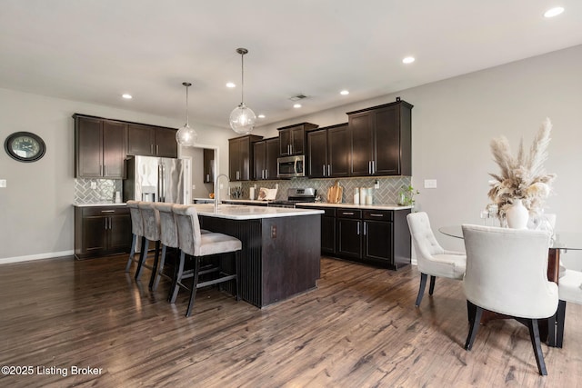 6803 Park Vista Way, Louisville, KY 40229 - kitchen featuring appliances with stainless steel finishes, tasteful backsplash, a kitchen bar, light countertops, and dark brown cabinetry