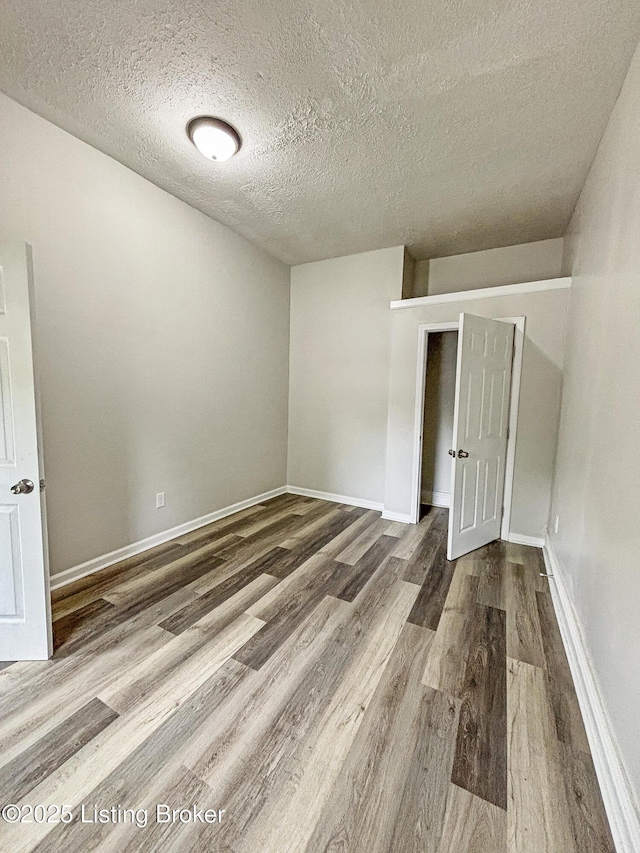 1724 Garland Ave, Louisville, KY 40210 - empty room with wood finished floors, a textured ceiling, and baseboards