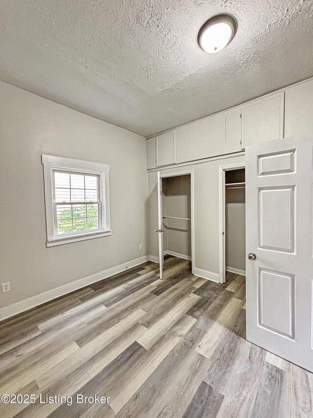 1724 Garland Ave, Louisville, KY 40210 - unfurnished bedroom featuring wood finished floors, a textured ceiling, and baseboards
