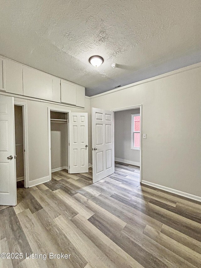 1724 Garland Ave, Louisville, KY 40210 - unfurnished bedroom with wood finished floors, a textured ceiling, baseboards, and a closet
