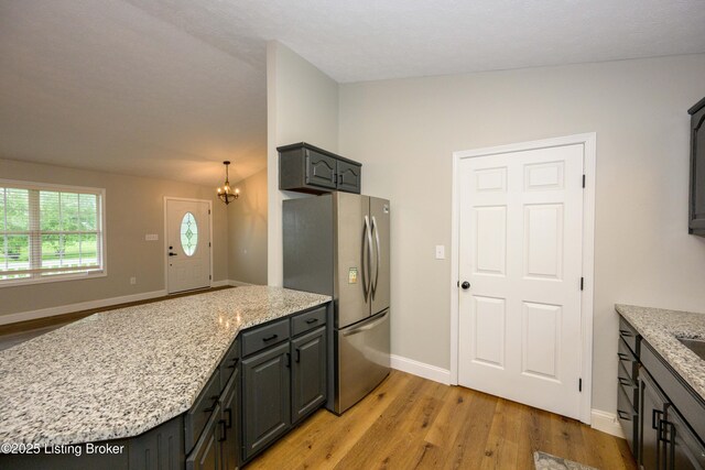 198 Cecilia Smiths Mill Rd, Cecilia, KY 42724 - kitchen with freestanding refrigerator, light wood-style floors, a peninsula, a chandelier, and light stone countertops