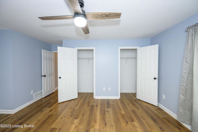 198 Cecilia Smiths Mill Rd, Cecilia, KY 42724 - unfurnished bedroom with two closets, wood finished floors, baseboards, and ceiling fan