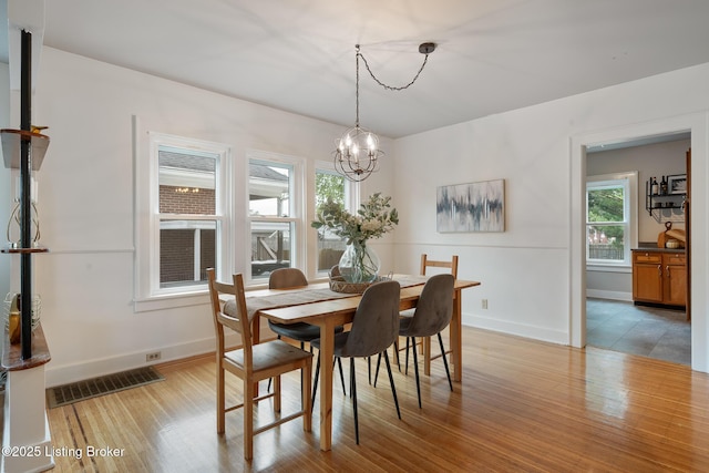 857 Melford Ave, Louisville, KY 40217 - dining room featuring a chandelier, healthy amount of natural light, light wood-type flooring, and baseboards