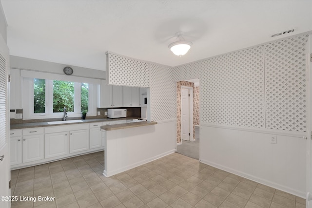 5212 Mary Clayton Ln, Crestwood, KY 40014 - kitchen featuring white microwave, white cabinetry, a wainscoted wall, a peninsula, and wallpapered walls