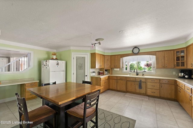 684 Cheslon Rd, Munfordville, KY 42765 - kitchen featuring freestanding refrigerator, light countertops, a sink, brown cabinetry, and glass insert cabinets