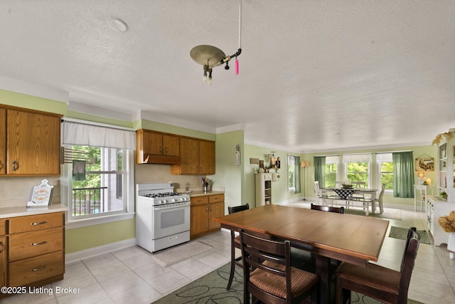 684 Cheslon Rd, Munfordville, KY 42765 - kitchen featuring gas range gas stove, brown cabinetry, a textured ceiling, light tile patterned floors, and light countertops