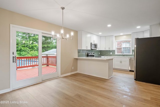 9707 Gateway Dr, Louisville, KY 40299 - kitchen with stainless steel appliances, a peninsula, light countertops, backsplash, and white cabinetry