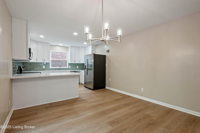9707 Gateway Dr, Louisville, KY 40299 - kitchen featuring appliances with stainless steel finishes, light countertops, a chandelier, light wood-style floors, and backsplash