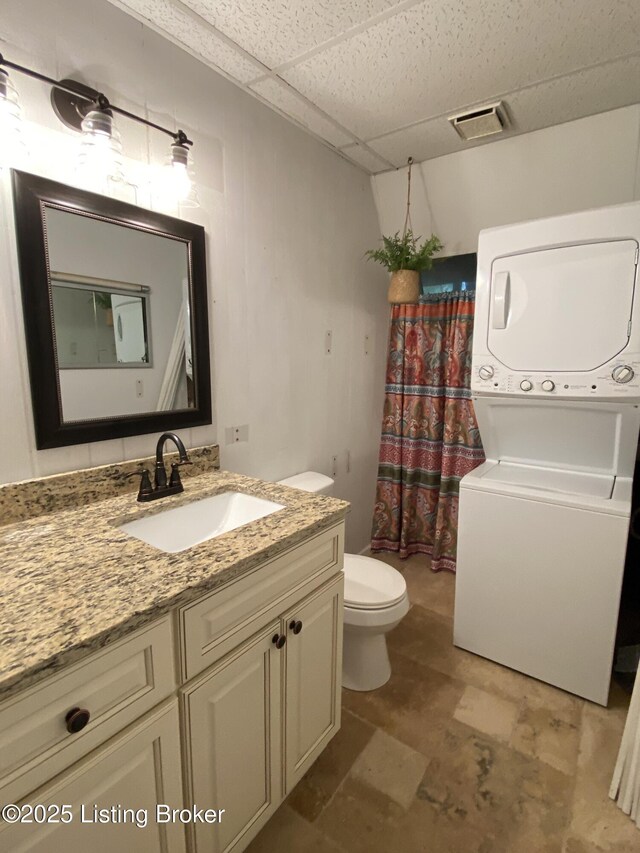 682 Hornback Mill Ln, Leitchfield, KY 42754 - bathroom with stacked washing machine and dryer, toilet, a paneled ceiling, vanity, and curtained shower