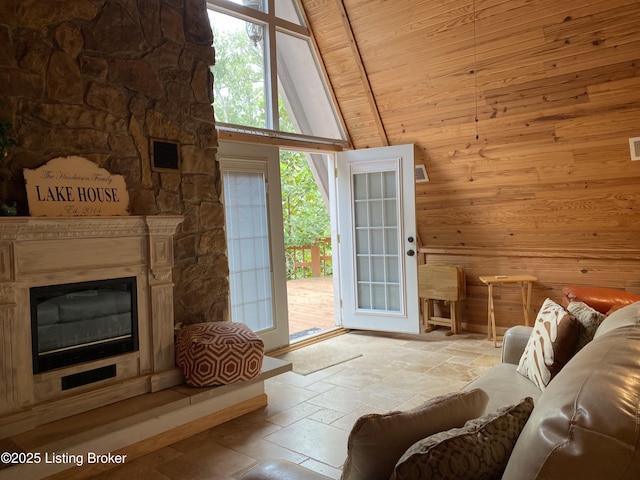 682 Hornback Mill Ln, Leitchfield, KY 42754 - living area featuring stone tile flooring, wood walls, a high ceiling, and a glass covered fireplace